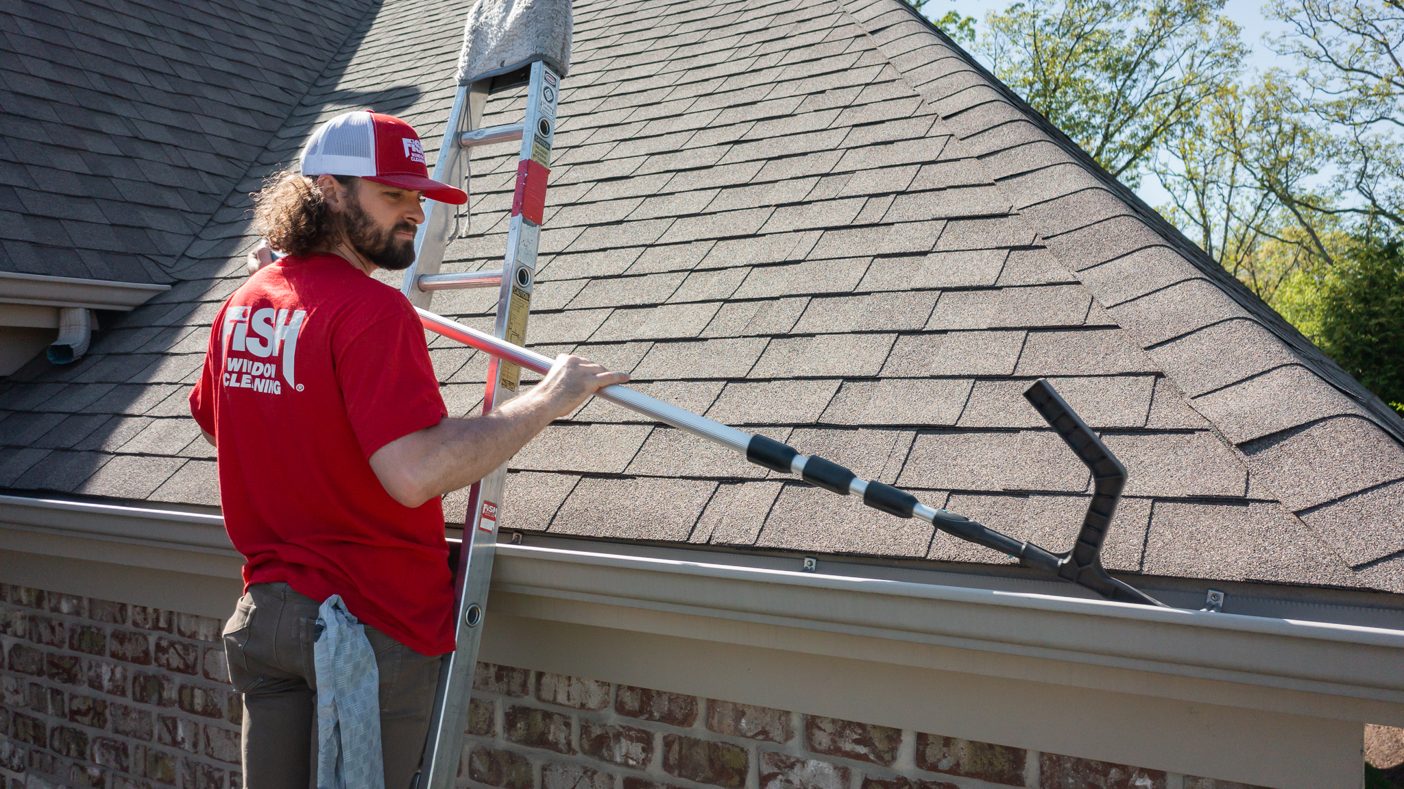 Fish Window Cleaner on Ladder Using Tool to Clean Gutters